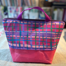 Load image into Gallery viewer, Plaid patterned bag with a pink base on a surface with books in the background
